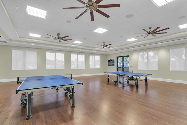 recreation room with wood finished floors, a raised ceiling, and baseboards