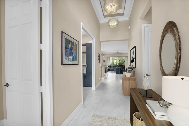 hall featuring a chandelier, marble finish floor, ornamental molding, and baseboards