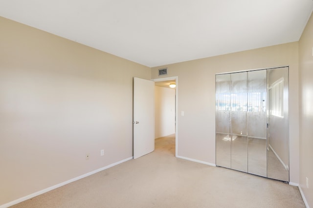 unfurnished bedroom featuring light colored carpet and a closet