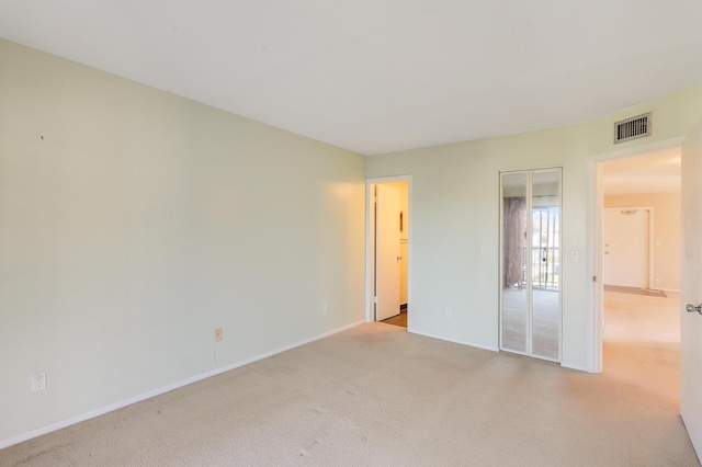 unfurnished bedroom with light colored carpet and a closet