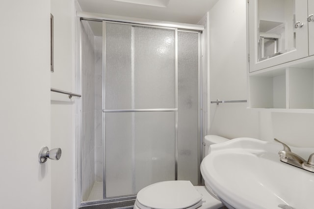 bathroom featuring walk in shower, toilet, and sink