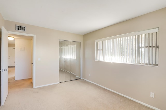 unfurnished bedroom featuring light carpet and a closet