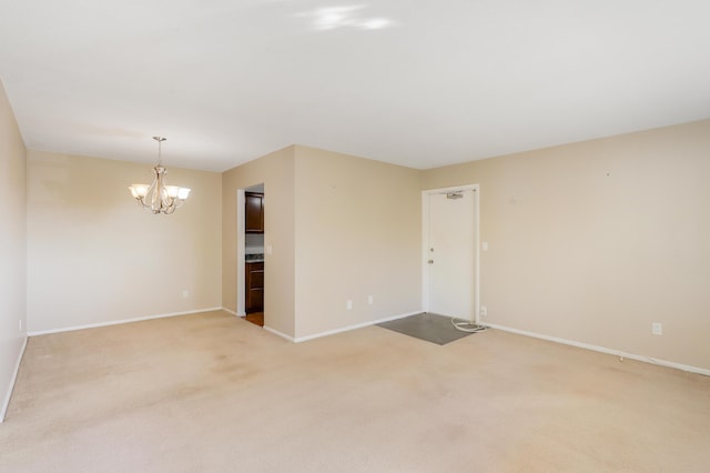 spare room with an inviting chandelier and light carpet