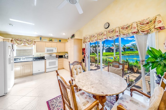 dining area featuring a water view, high vaulted ceiling, ceiling fan, and sink