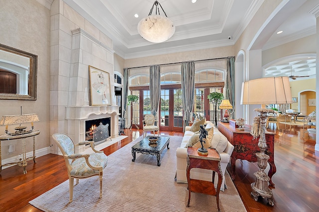 living room with a high end fireplace, french doors, ornamental molding, ceiling fan, and wood-type flooring