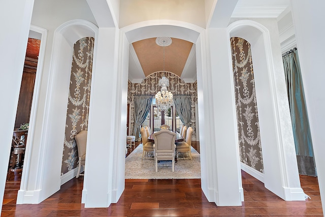 interior space with a chandelier, dark hardwood / wood-style floors, vaulted ceiling, and ornamental molding