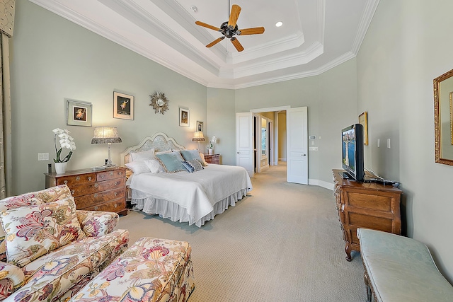 carpeted bedroom with a towering ceiling, a tray ceiling, ceiling fan, and ornamental molding