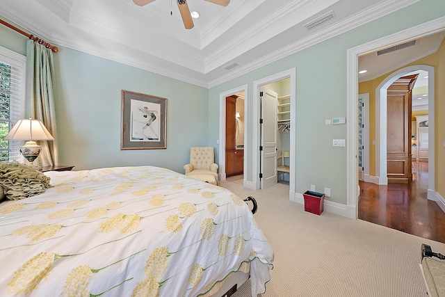 bedroom featuring a walk in closet, ornamental molding, ceiling fan, carpet floors, and a closet