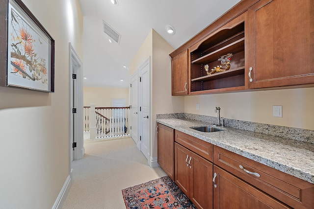 kitchen featuring light stone countertops, sink, and light carpet