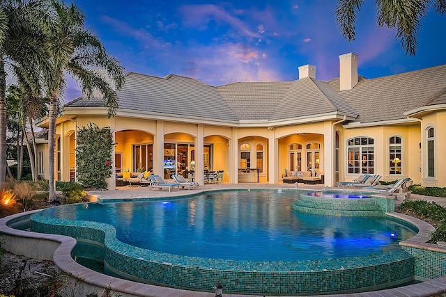 pool at dusk featuring outdoor lounge area and a patio