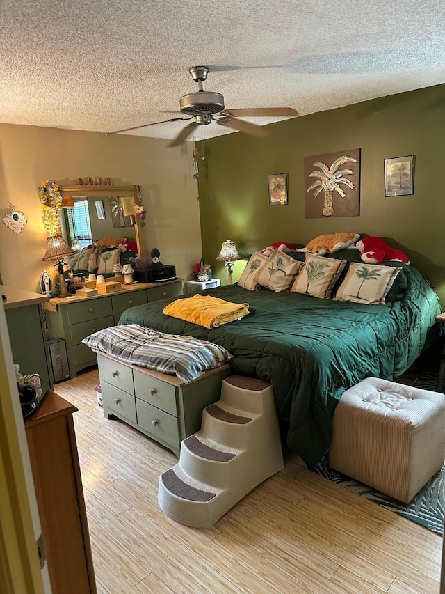 bedroom with ceiling fan, a textured ceiling, and light hardwood / wood-style flooring