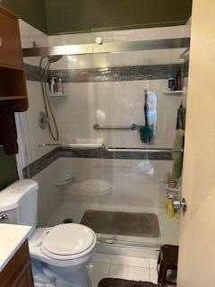 bathroom with vanity, tiled shower, tile patterned floors, and toilet