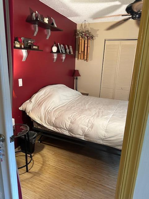 bedroom with a closet, ceiling fan, hardwood / wood-style floors, and a textured ceiling