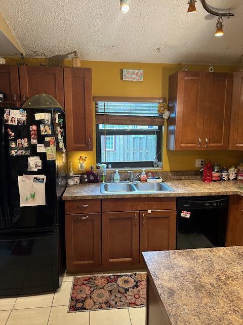 kitchen with sink, light tile patterned floors, black appliances, and a textured ceiling