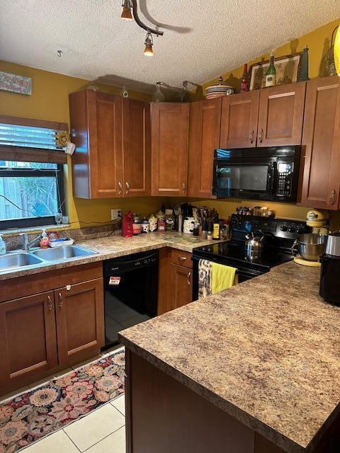 kitchen with sink, light tile patterned floors, a textured ceiling, and black appliances