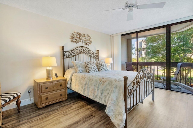 bedroom featuring ceiling fan, expansive windows, a textured ceiling, access to outside, and hardwood / wood-style flooring