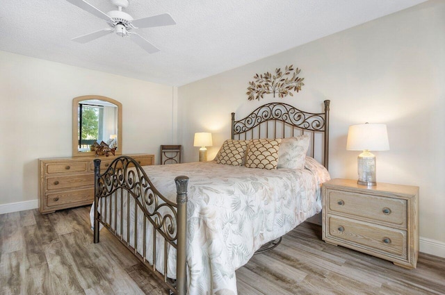 bedroom with ceiling fan, wood-type flooring, and a textured ceiling