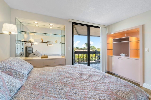 bedroom featuring access to exterior, a textured ceiling, and dark wood-type flooring