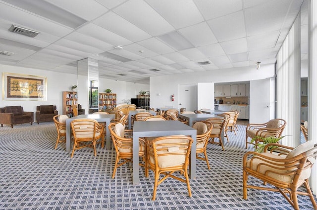 carpeted dining area featuring a drop ceiling