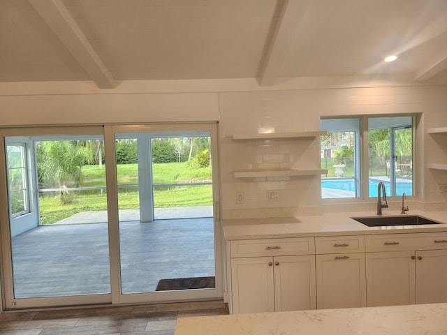 doorway to outside with beamed ceiling, light hardwood / wood-style flooring, and sink