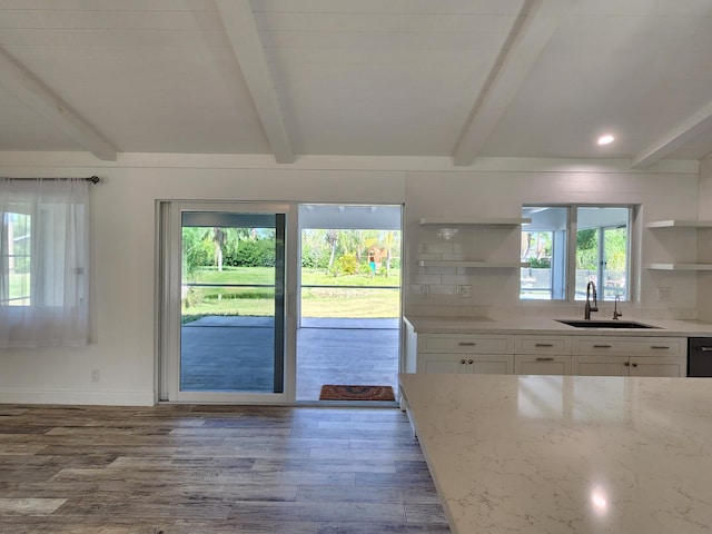 kitchen featuring light stone countertops, sink, hardwood / wood-style floors, plenty of natural light, and white cabinets