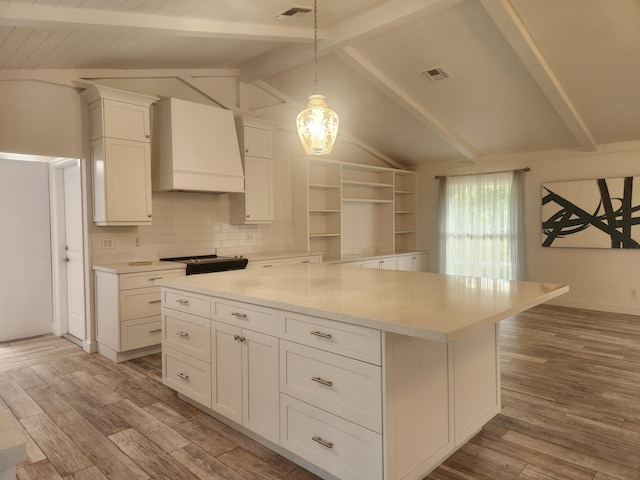 kitchen featuring premium range hood, hanging light fixtures, lofted ceiling with beams, and light wood-type flooring