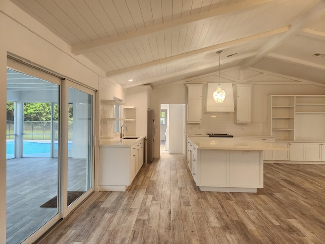 kitchen with pendant lighting, white cabinets, lofted ceiling with beams, light wood-type flooring, and custom range hood