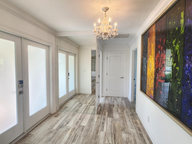 interior space featuring a chandelier, french doors, light hardwood / wood-style floors, and ornamental molding