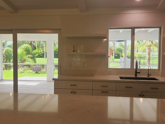 kitchen featuring backsplash, sink, white cabinets, and beam ceiling