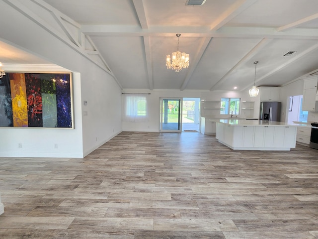 kitchen featuring white cabinets, decorative light fixtures, lofted ceiling with beams, and appliances with stainless steel finishes