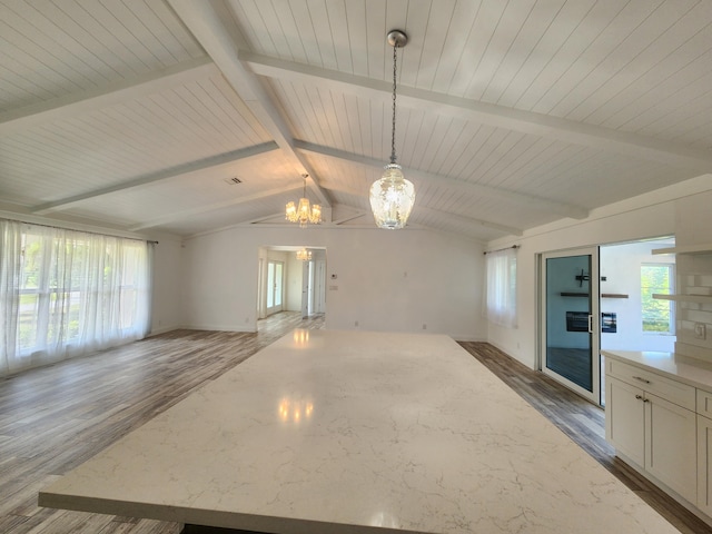 unfurnished living room with a chandelier, hardwood / wood-style floors, and lofted ceiling with beams