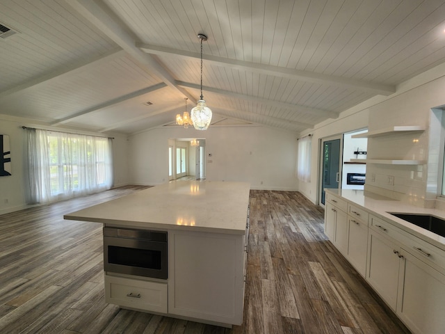 kitchen featuring white cabinets, vaulted ceiling with beams, decorative light fixtures, and dark hardwood / wood-style floors