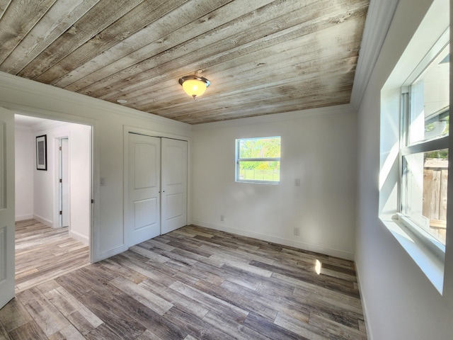 unfurnished bedroom featuring light wood-type flooring, wooden ceiling, ornamental molding, and a closet