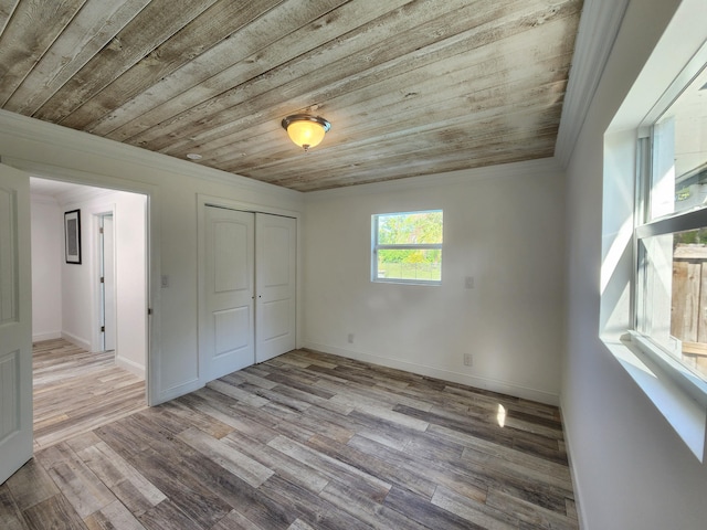 unfurnished bedroom with light hardwood / wood-style floors, a closet, crown molding, and wood ceiling