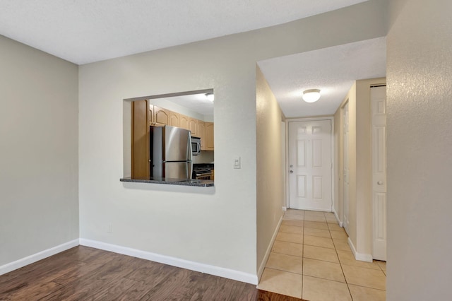 corridor featuring a textured ceiling and light hardwood / wood-style flooring