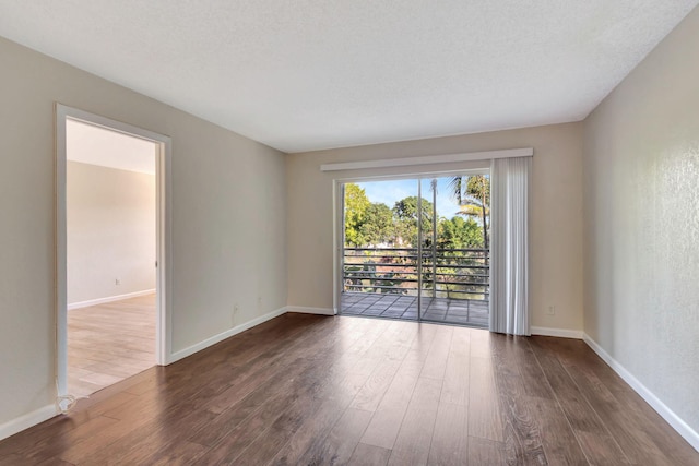 unfurnished room with dark hardwood / wood-style flooring and a textured ceiling