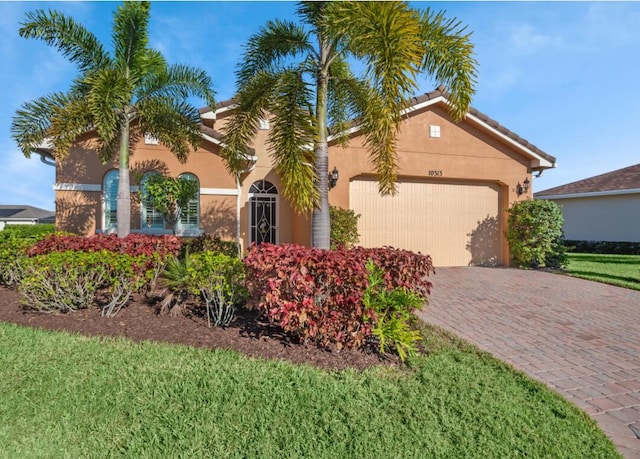10313 SW Fernwood Ave, Port Saint Lucie, FL 34987 - view of front of property featuring an attached garage, stucco siding, decorative driveway, and a front lawn