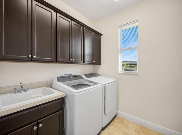 washroom featuring separate washer and dryer, sink, light tile patterned floors, and cabinets