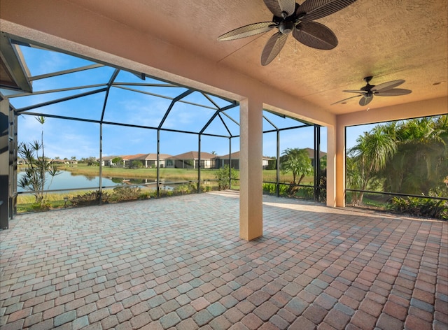 view of patio / terrace with a lanai, ceiling fan, and a water view