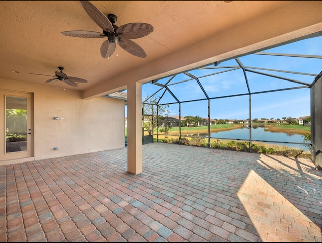 view of patio featuring a water view, ceiling fan, and a lanai