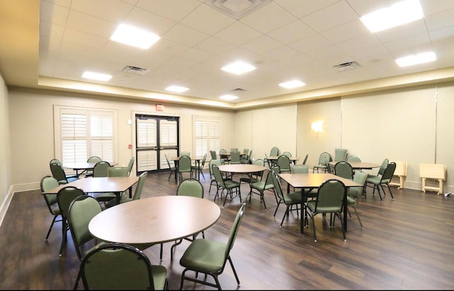 dining area featuring dark wood-type flooring, a drop ceiling, and a tray ceiling