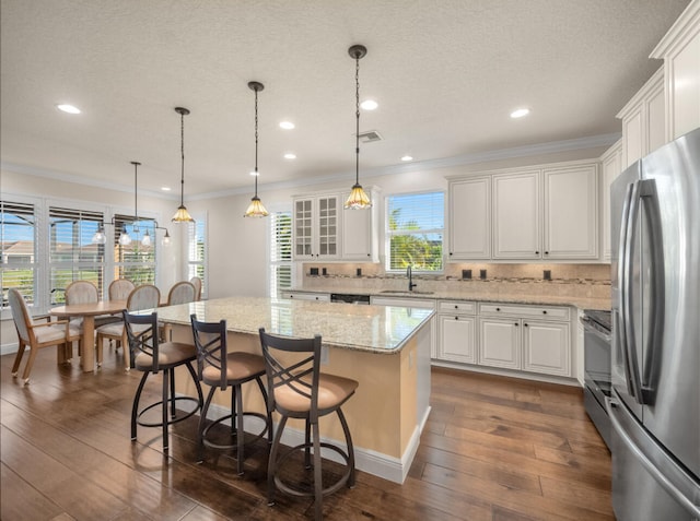 kitchen with a center island, stainless steel appliances, dark hardwood / wood-style flooring, a kitchen bar, and white cabinets