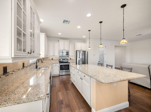 kitchen featuring stainless steel appliances, a kitchen island, sink, and a kitchen breakfast bar