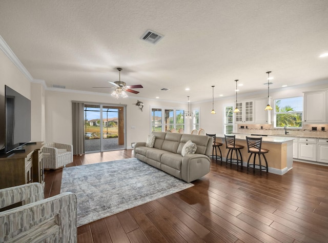 living room with crown molding, ceiling fan, a healthy amount of sunlight, and dark hardwood / wood-style floors