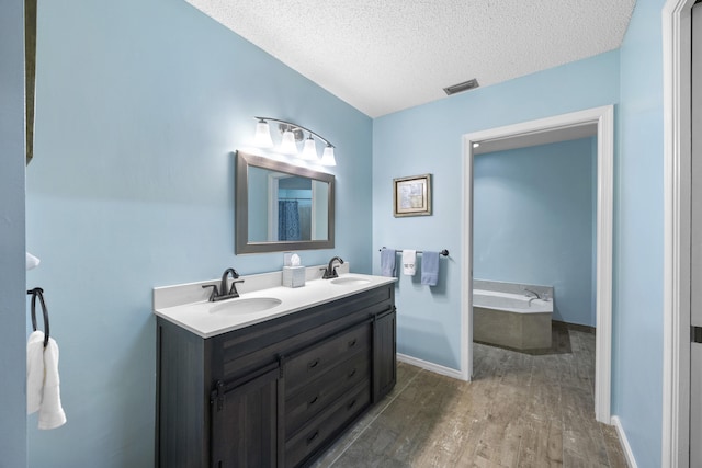 bathroom featuring vanity, a textured ceiling, hardwood / wood-style flooring, and a tub