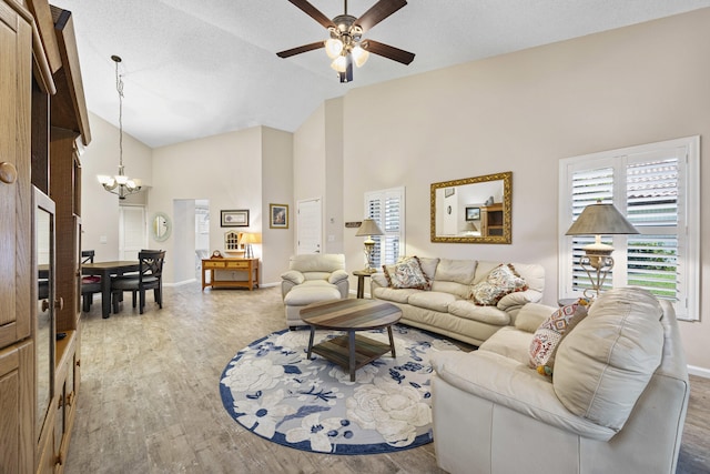 living room with a textured ceiling, high vaulted ceiling, ceiling fan with notable chandelier, and hardwood / wood-style flooring