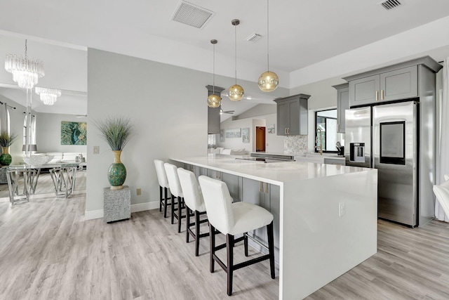 kitchen with kitchen peninsula, stainless steel fridge, light hardwood / wood-style flooring, and a breakfast bar area