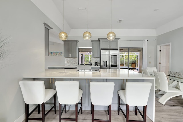 kitchen featuring gray cabinetry, decorative light fixtures, a kitchen breakfast bar, and appliances with stainless steel finishes