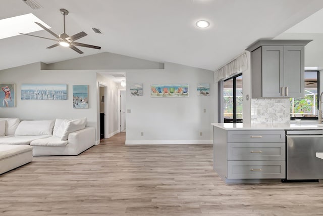 kitchen with lofted ceiling with skylight, stainless steel dishwasher, ceiling fan, gray cabinets, and light wood-type flooring