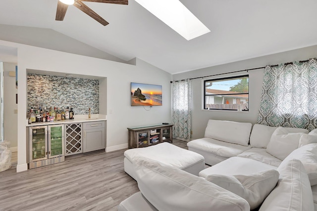 living room with ceiling fan, beverage cooler, light hardwood / wood-style floors, lofted ceiling, and bar